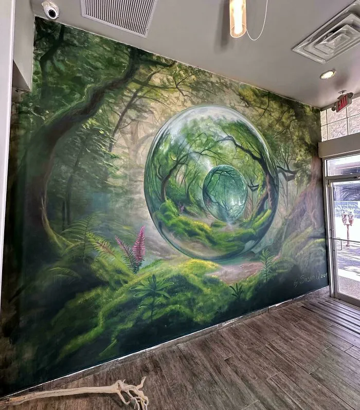 Murales con efecto surrealista mostrando un bosque reflejado en esferas de cristal en un espacio interior moderno.