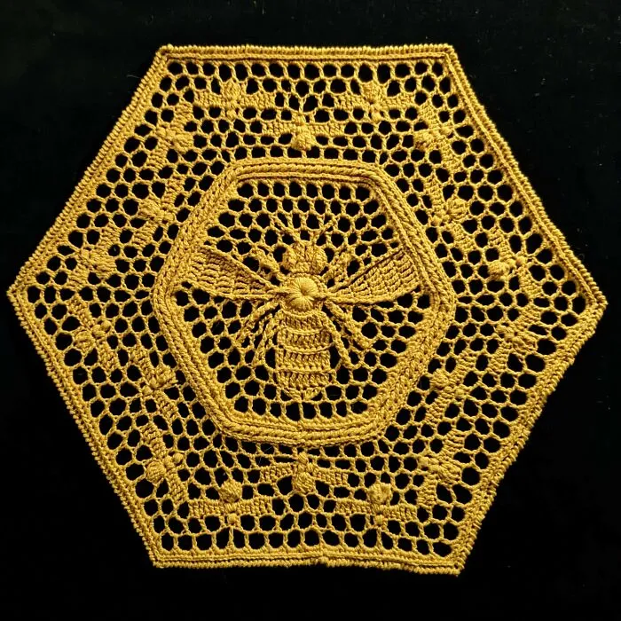 Hexagonal crochet featuring a detailed bee pattern on black background.