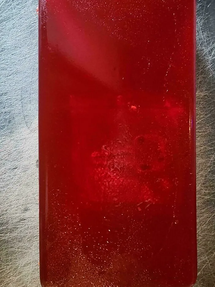 Close-up of a red gelatin block with texture and light reflections.