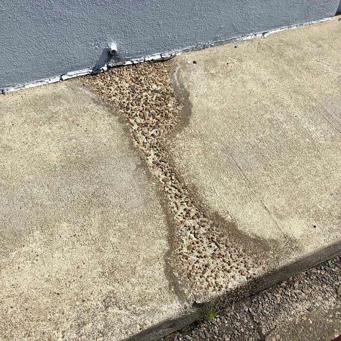 Años de flujo de agua de esta tubería de drenaje han desgastado este trozo de acera hasta la base rocosa.