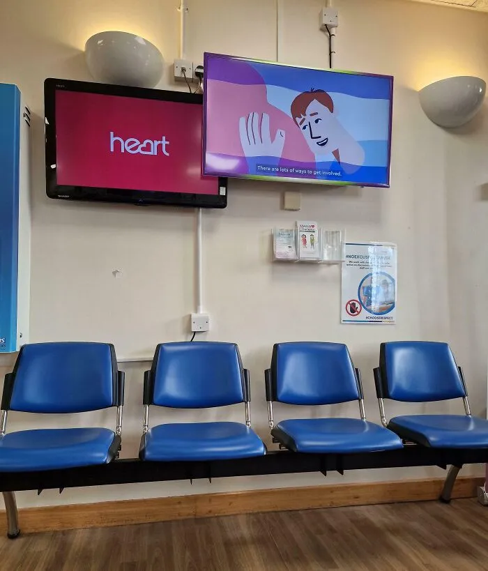 Estos dos televisores superpuestos tienen el volumen encendido en la sala de espera del hospital