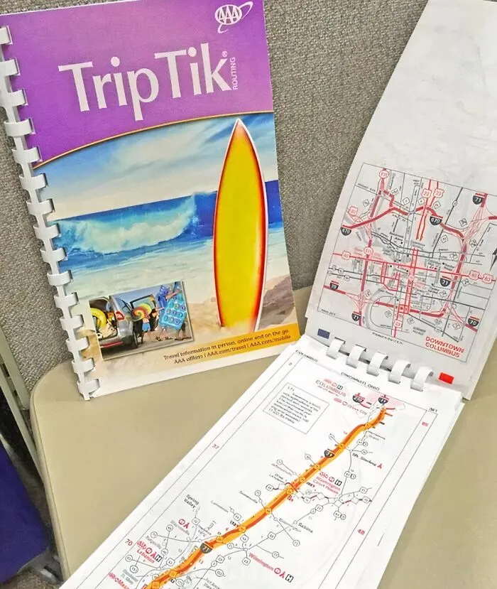 Gen X TripTik map booklet open on a table, featuring a colorful surfboard cover and detailed map pages.