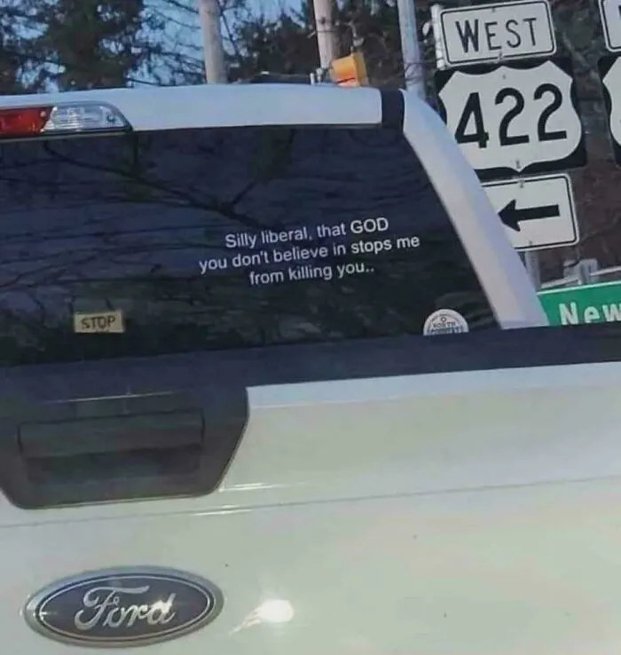 Rear of white Ford truck with decal about God and killing statement