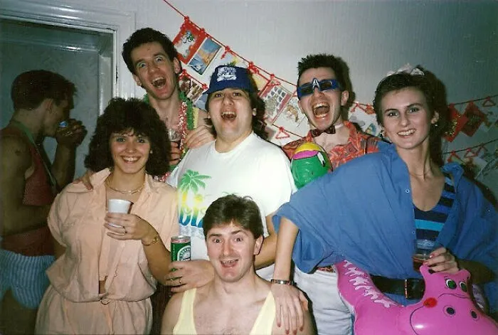 Group of friends at a party wearing vibrant 80s fashion trends, including funky sunglasses and colorful shirts.