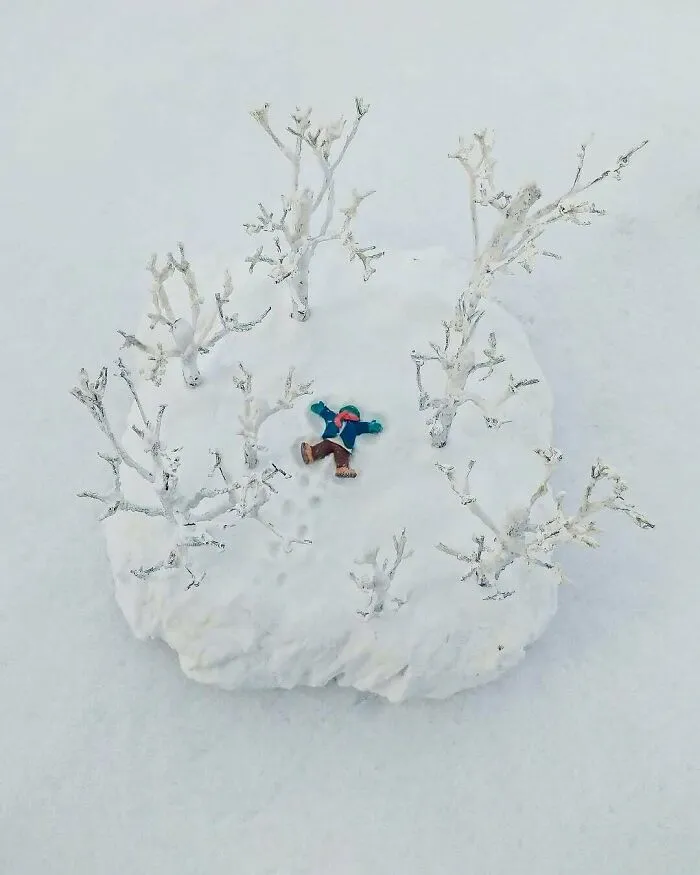Miniature person making a snow angel surrounded by tiny snowy trees, showcasing creative DIY project ideas.