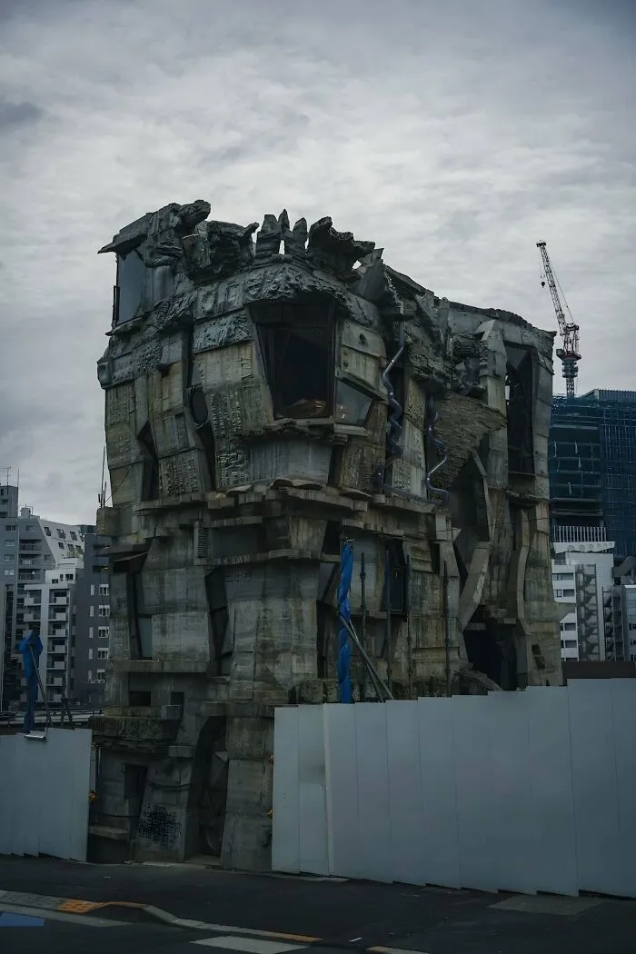 Dark, ominous building with jagged concrete structures and broken windows, evoking supervillain headquarters vibes.