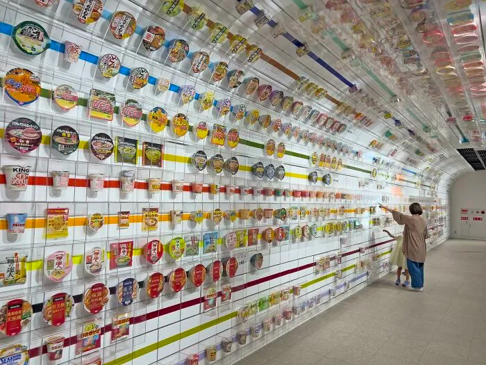 Wall of instant noodles at a museum in Japan, featuring colorful packaging.