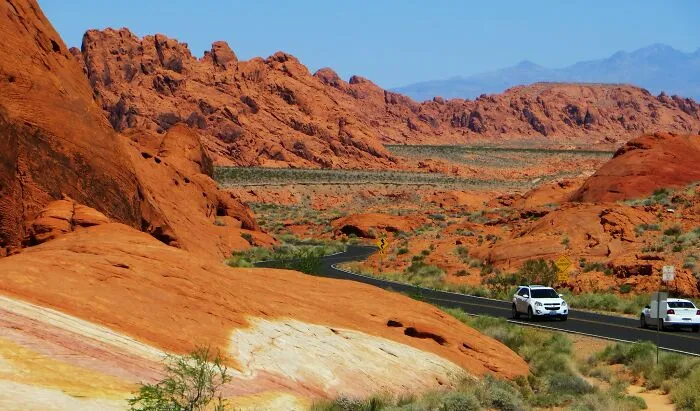 Scenic desert road winding through rocky landscape under clear blue sky, highlighting amazing views states.