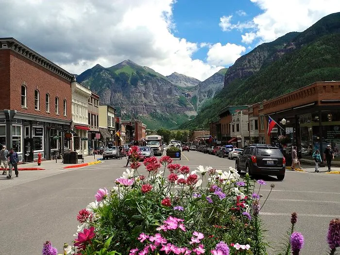 Main street with flowers and cars, framed by mountains in one of the amazing-views states.