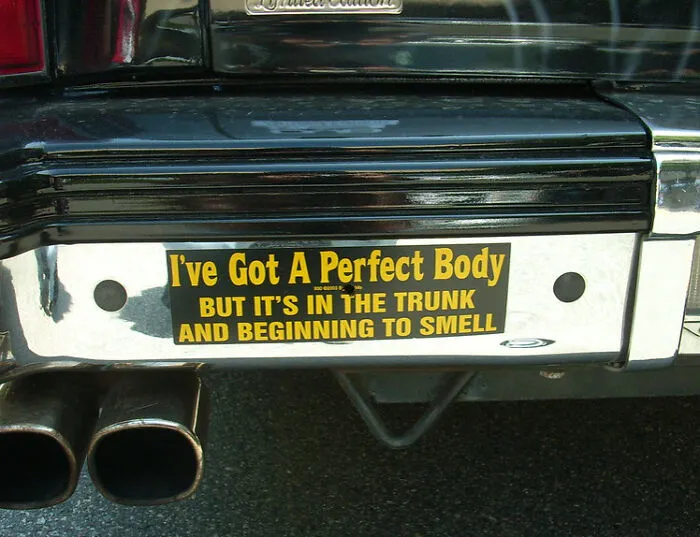 Funny bumper sticker on a black car: "I've Got A Perfect Body, But It's In The Trunk And Beginning To Smell."