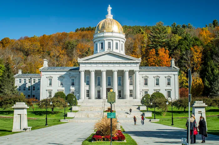 Historic white capitol building with a golden dome, surrounded by autumn trees, showcasing amazing views in states.