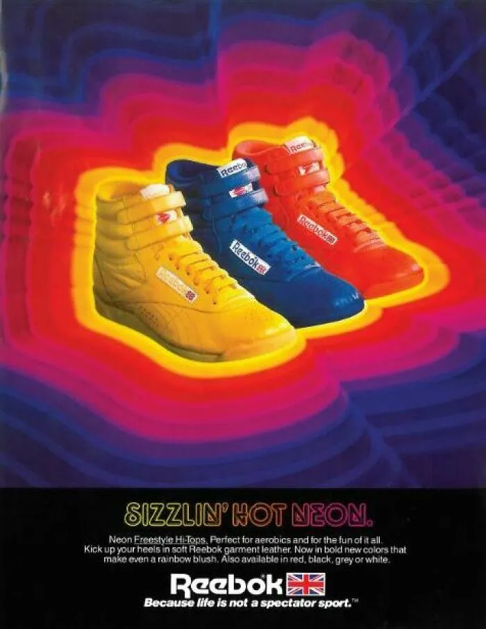 Neon Reebok sneakers in yellow, blue, and red against a vibrant background, showcasing iconic 80s fashion trends.