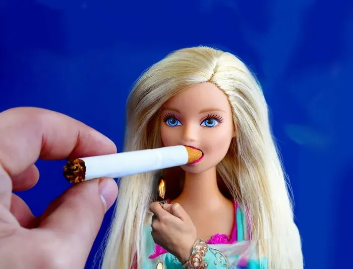 Turkish artist collage featuring a doll holding a cigarette to its mouth with a blue background.
