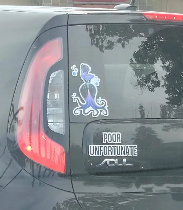 Car with funny bumper sticker reading "Poor Unfortunate" and a colorful cartoon octopus decal.