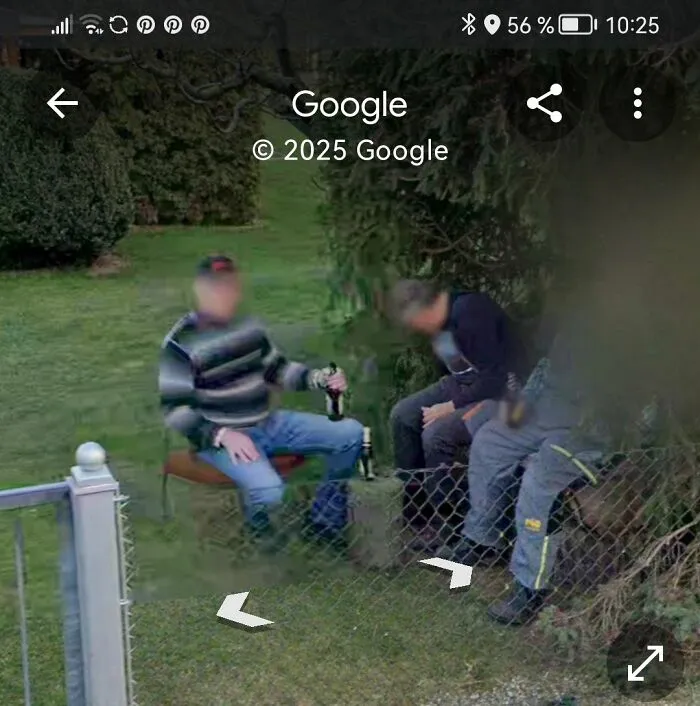 People spotted by Google Earth sitting on chairs near a fence in a garden setting.