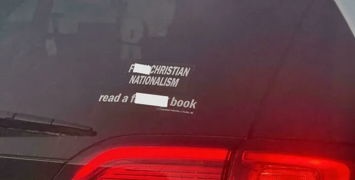 Funny bumper sticker on a car rear window with a provocative message on nationalism and reading.