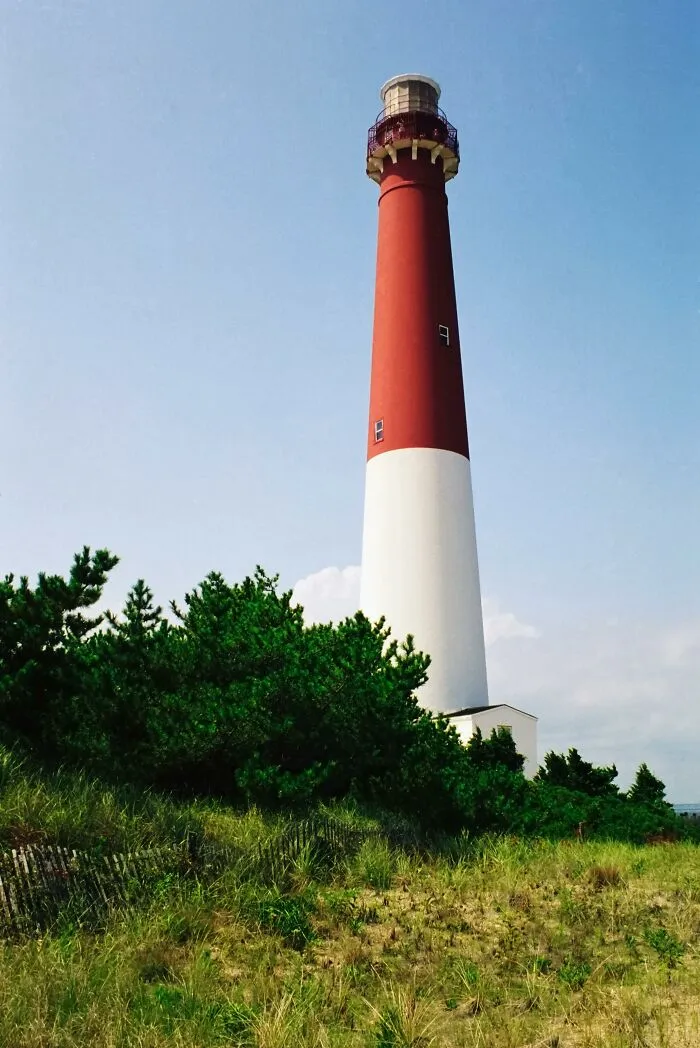 Lighthouse by the beach with people enjoying the amazing views and sunny day.