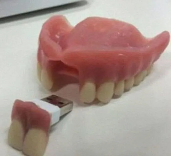 Memoria USB rara con forma de dentadura sobre una mesa.