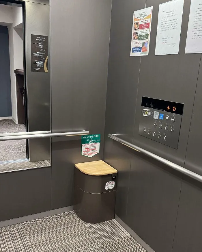 Elevator in Japan featuring an emergency seat and informational signs on the wall, showcasing Interesting-Japan-Pics.