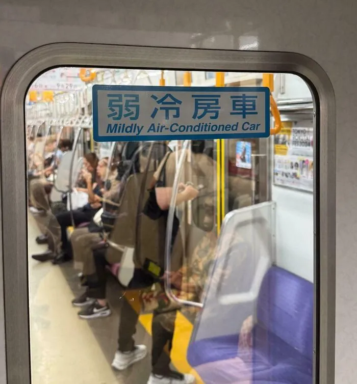 A sign reading "Mildly Air-Conditioned Car" on a Japanese train with passengers inside, representing interesting Japan pics.