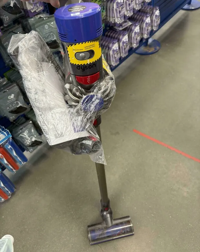 Dyson cordless vacuum cleaner thrift store find displayed in plastic wrap on store floor with shelves in background