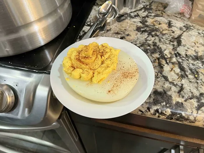 Close-up of a moderately interesting deviled egg with unusual presentation and seasoning on a kitchen counter.