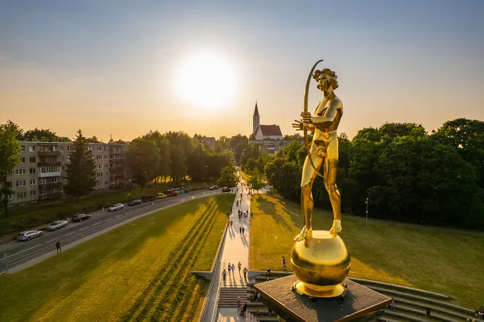 Golden statue overlooking a Lithuanian cityscape with sunset, providing a stunning bird’s-eye view.