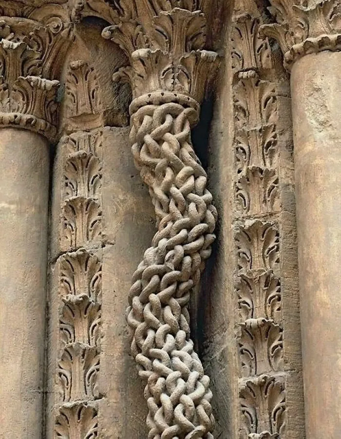 Intricate carved column detail from an ancient artefact, showcasing elaborate looping patterns and designs.