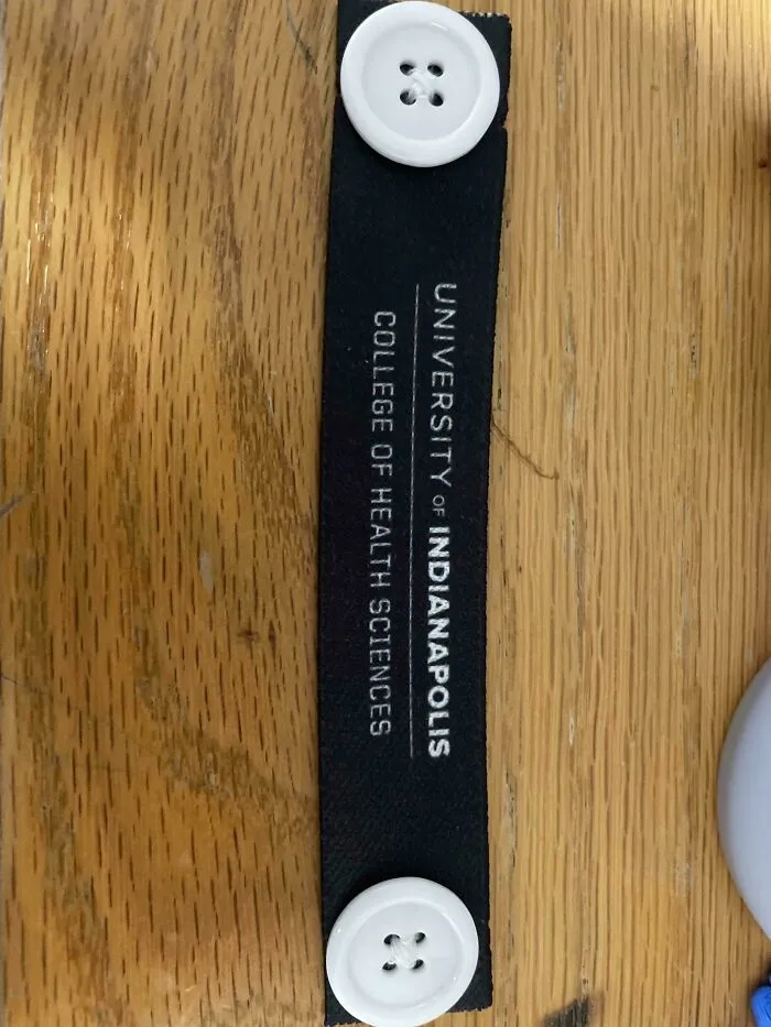 This Came In A Swag Bag At A Career Fair. It Is Two Buttons On Either Side Of An Elastic Strip. No Holes. What Is This?