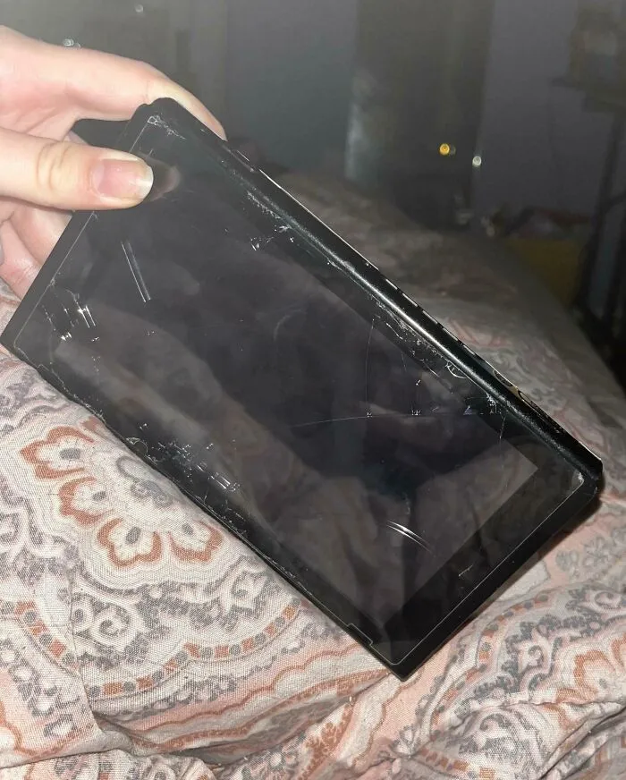 Móvil roto sostenido por una mano, ejemplo de comportamiento masculino descuidado.