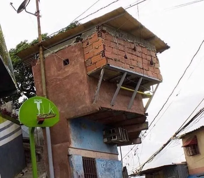 Edificio con fallos arquitectónicos, ladrillos expuestos y soporte inestable, causando una impresión humorística.