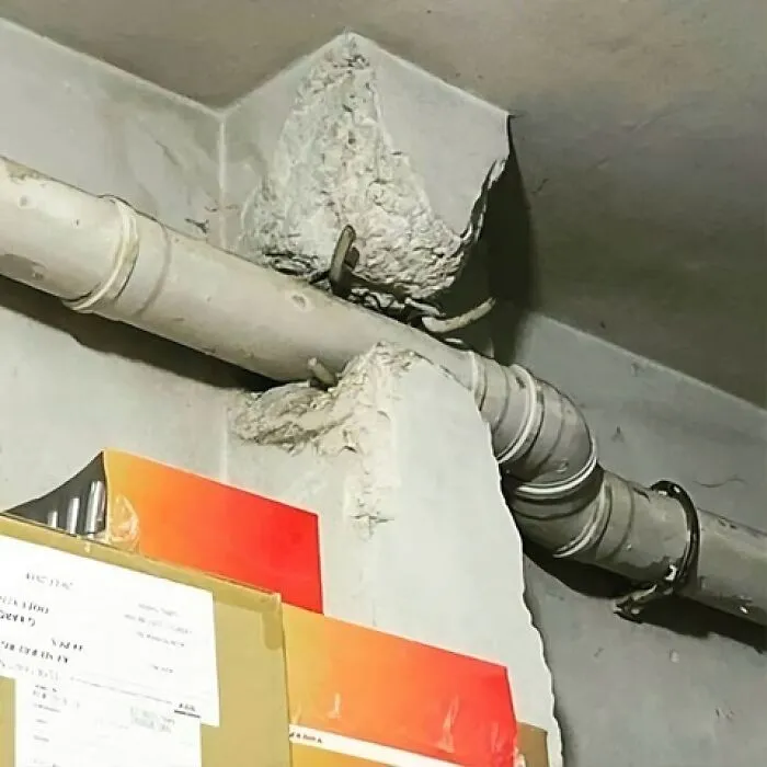Un fallo de arquitectura gracioso con tubería incrustada en una columna de concreto.