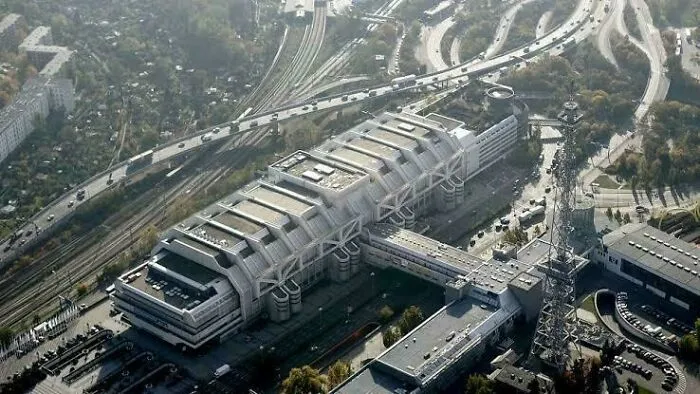 Aerial view of a large brutalist building with an ominous design, resembling a supervillain headquarters with evil auras.