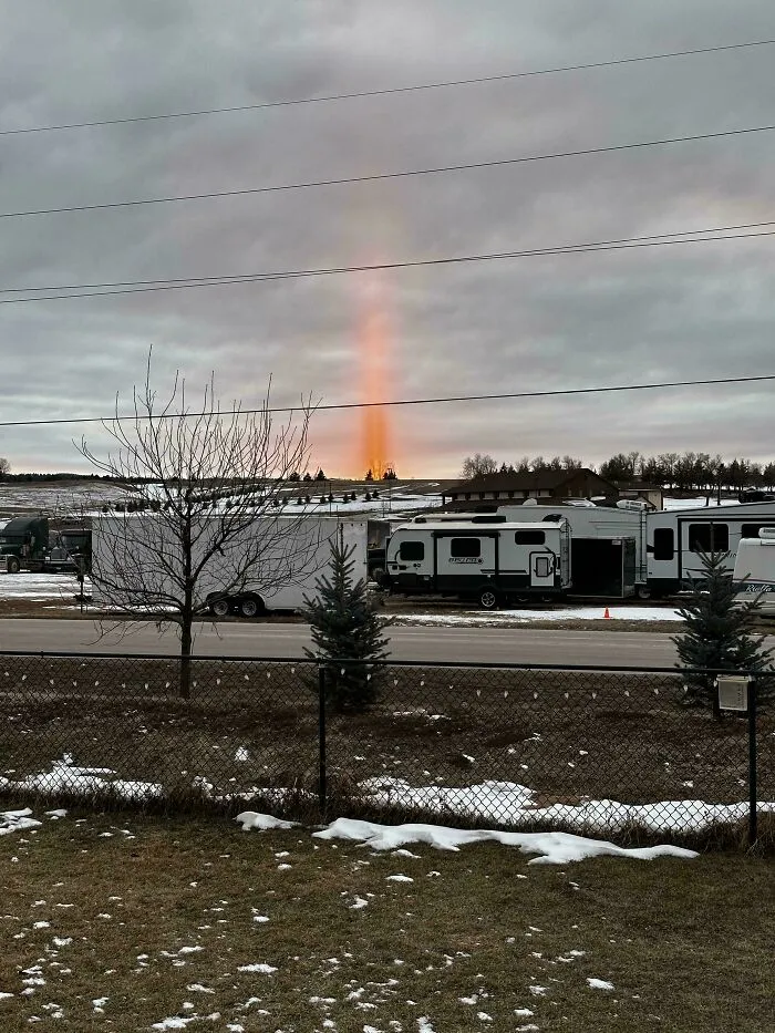 A vertical light beam in the sky over trailers, creating an oddly terrifying scene.