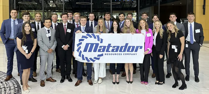 Group of professionals in business attire holding Matador Resources Company banner, illustrating outrageous job requirements challenge.