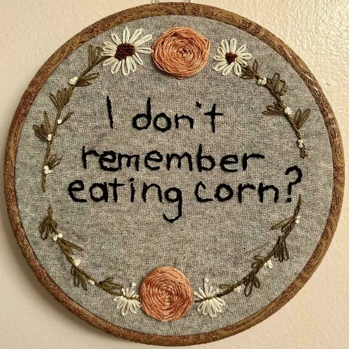 Embroidery hoop art with text and floral designs showcasing incredible and beautiful embroidery skills on gray fabric.