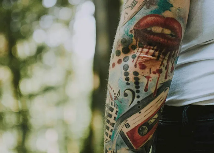 Arm with creative tattoo design, highlighting colorful ink art in natural light.