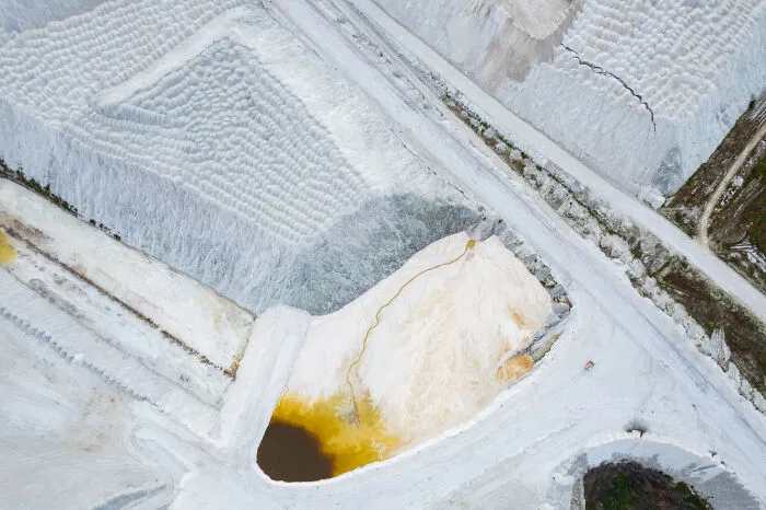 Aerial view of Lithuania's stunning landscape with textured white terrain and colorful pond.