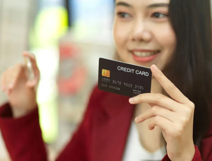 Person smiling and holding a credit card, illustrating how rich people can appear out of touch with reality.