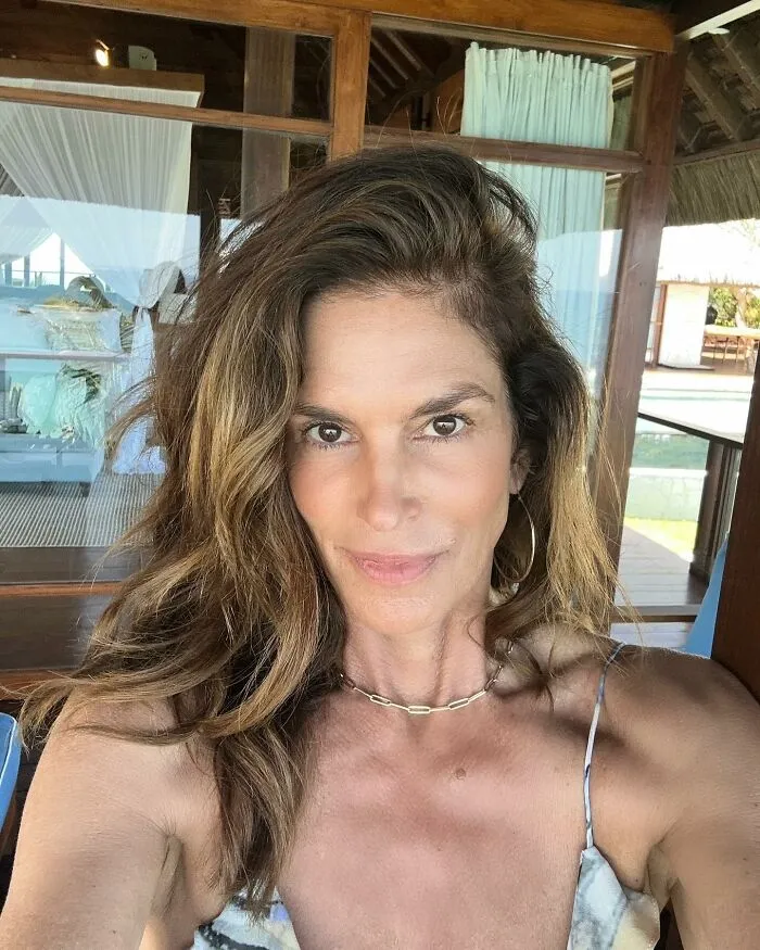 Celebrity without makeup taking a selfie, with natural hair in a relaxed setting.