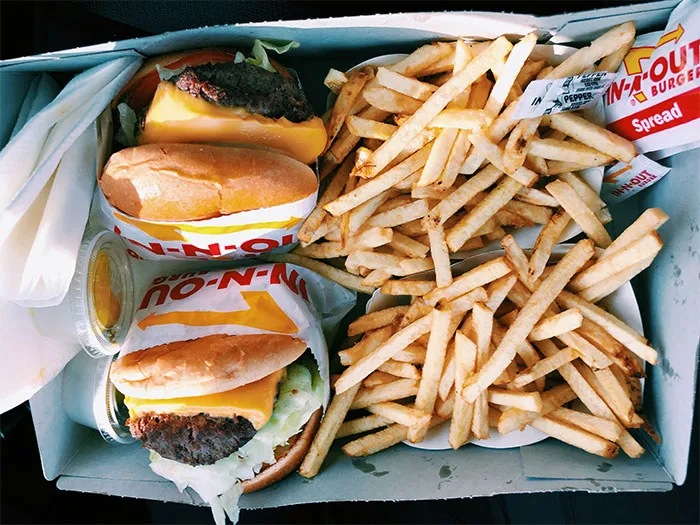 In-N-Out burgers and fries in a takeout box, highlighting rich people's indulgence.