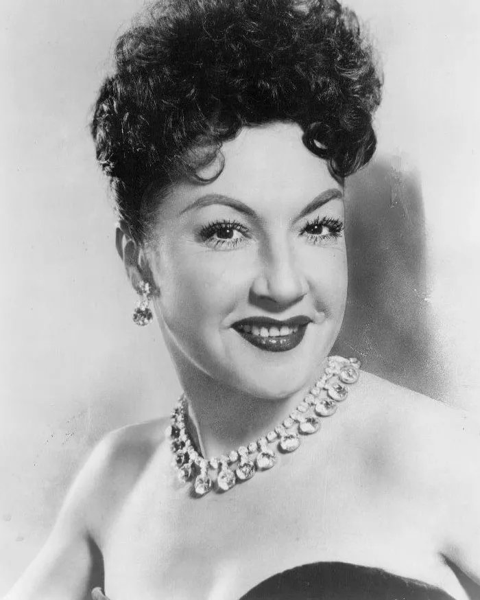Elegant woman with curly hair and a pearl necklace, often considered a singer who shouldn't have made it big.