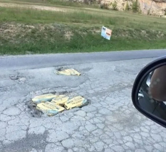 Huecos en la carretera llenos de bolsas de cemento en una escena rara.