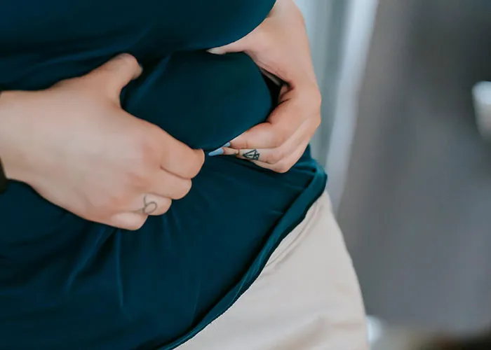 Person holding their stomach, illustrating challenges of being overweight.