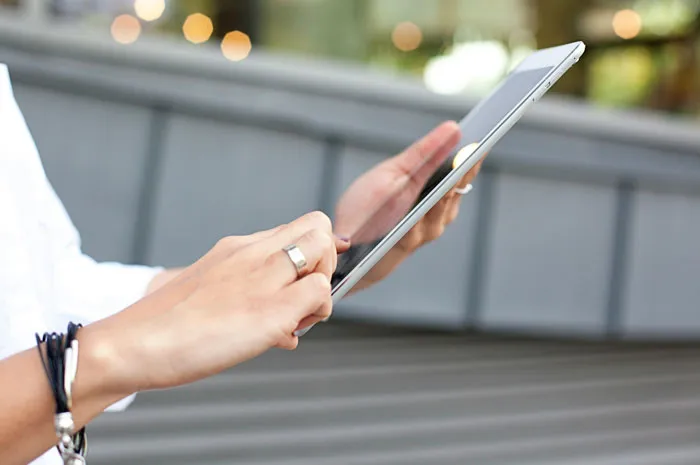 Person with a ring using a digital tablet, highlighting rich people's lifestyle.