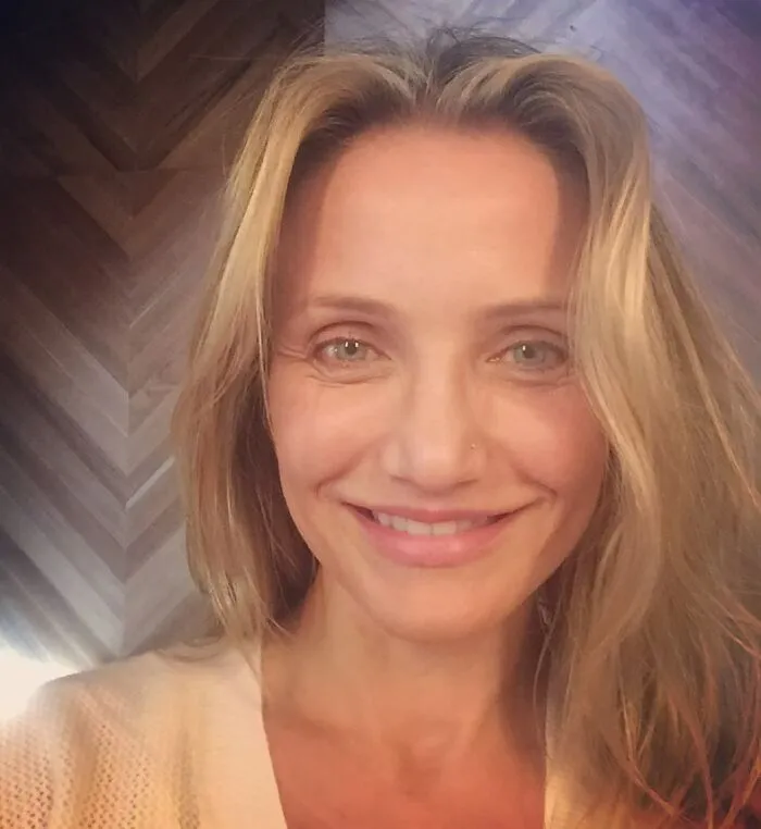 A person smiling without makeup, highlighting natural beauty.
