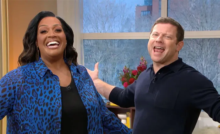 Smiling TV show hosts in a lively setting, embodying chemistry.