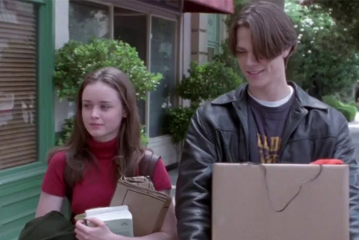 A young couple walking outdoors, each holding books, representing a TV couple with little chemistry.
