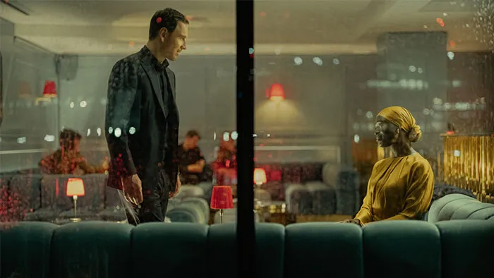 A man and woman in a dimly lit lounge, separated by glass, depicting a lack of chemistry.