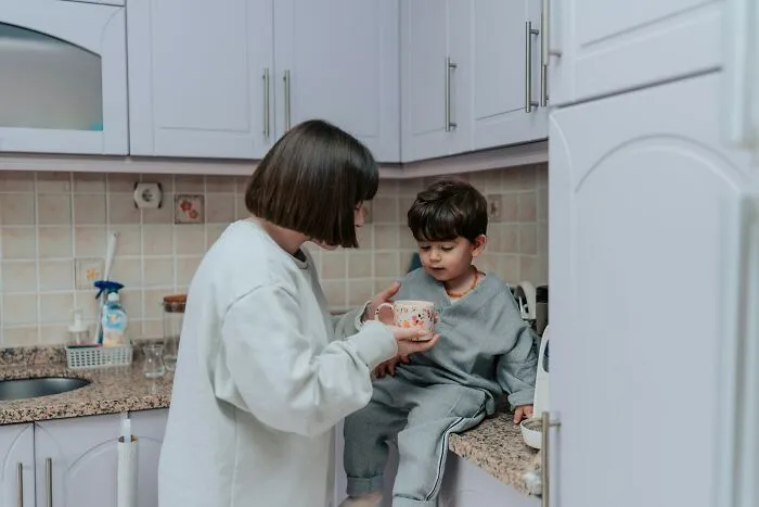 Woman and child in a kitchen sharing a moment, illustrating life lessons and financial decisions.